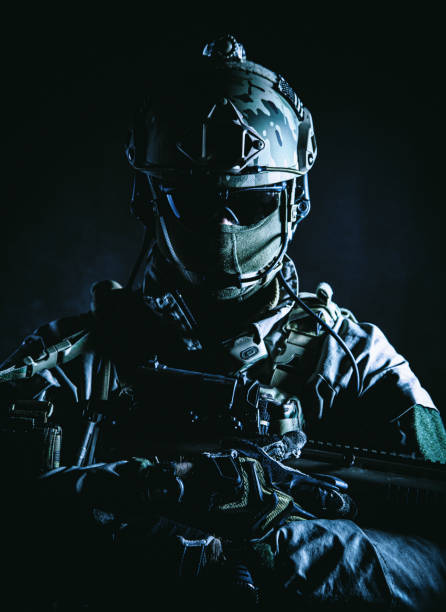 istock Army soldier in Protective Combat Uniform holding Special Operations Forces Combat Assault Rifle. Studio shot, dark contrast, cropped, black dark background, contour shot 1421959487