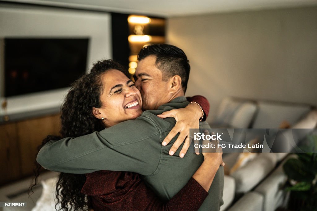 Mid adult couple embracing in the living room at home Couple - Relationship Stock Photo