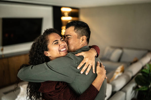 casal adulto médio abraçando na sala de estar em casa - boa notícia - fotografias e filmes do acervo