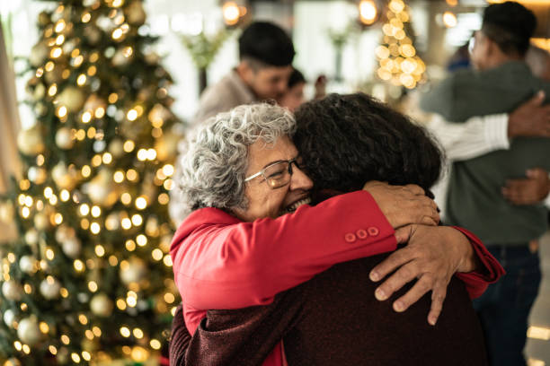Senior woman hugging her daughter on christmas at home stock photo