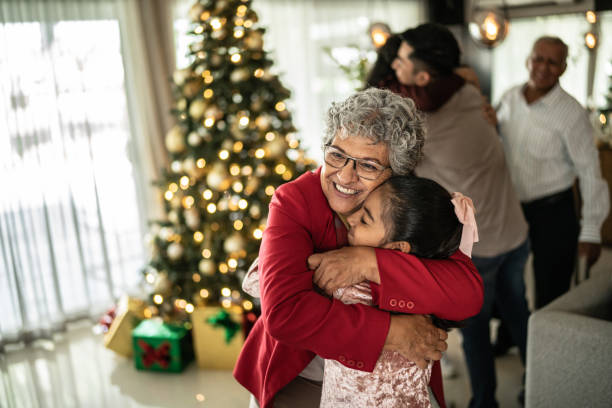 grand-mère serrant sa petite-fille dans ses bras à noël à la maison - culture latino américaine photos et images de collection