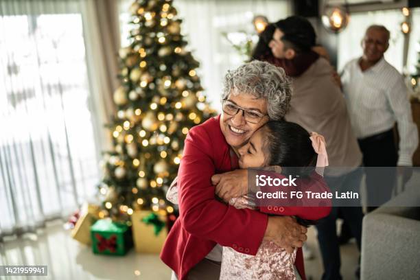 Grandmother Hugging Her Granddaughter On Christmas At Home Stock Photo - Download Image Now
