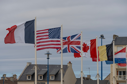 Two flags on flagpole blowing in the wind.  Clear Blue background.
