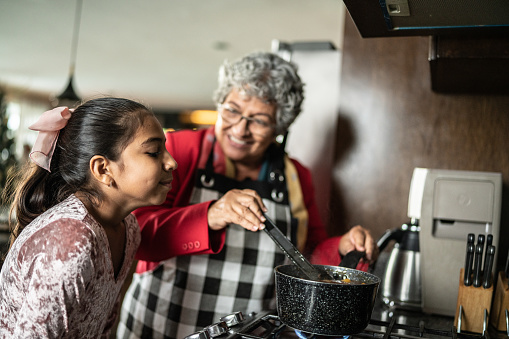 Nieta oliendo la comida de la abuela en la cocina de casa photo