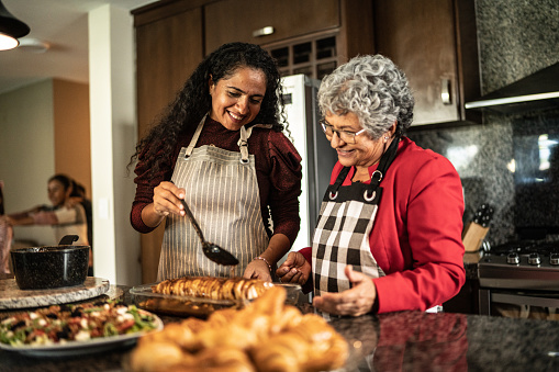 Mother and daughter preparing food at the kitchen counter at home