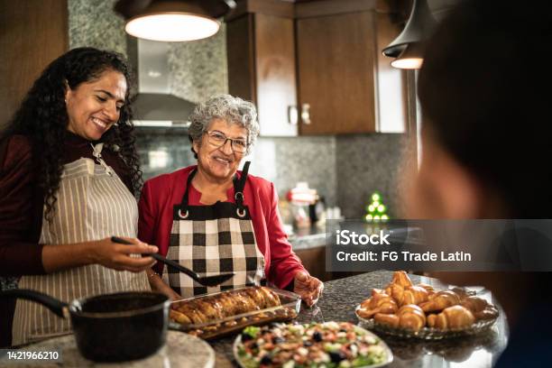 Mother And Daughter Talking While Preparing Food At Kitchen Counter At Home Stock Photo - Download Image Now