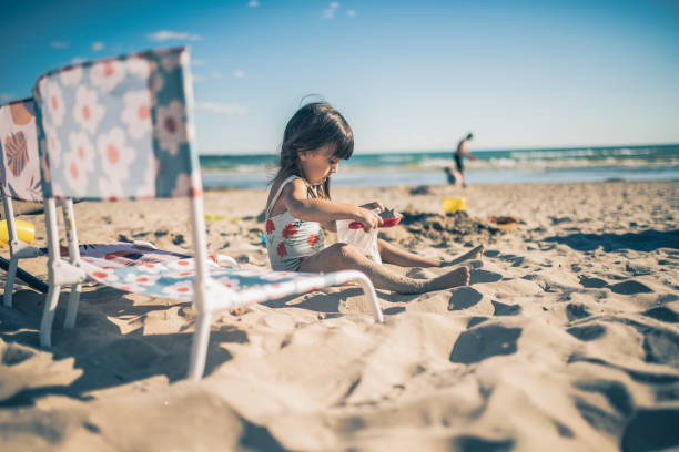 Little girl playing with sand by the beach