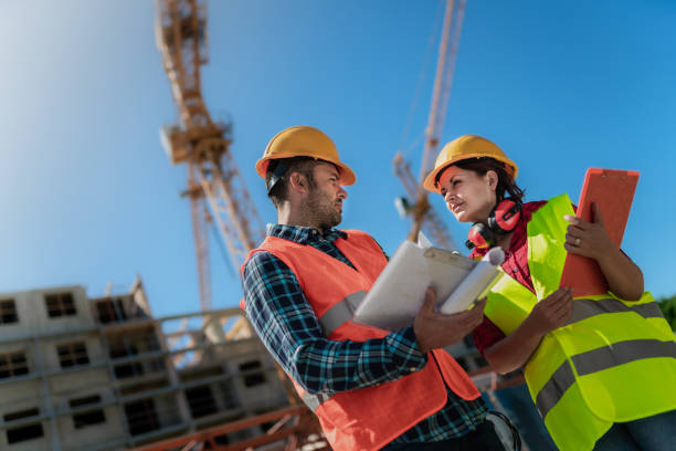 istock Workers on construction site with construction cranes / towers high above. 1421973091