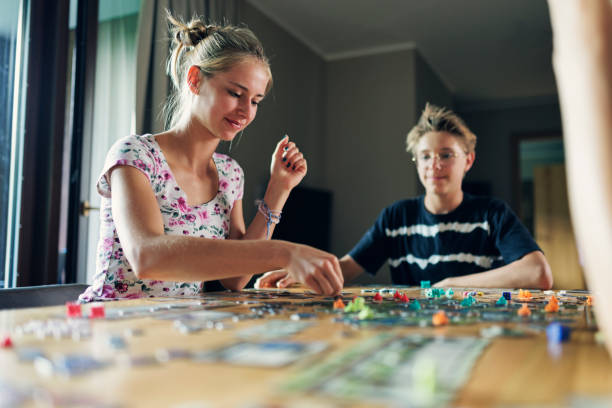 自宅で一緒に大きなモダンなボードゲームをプレイする10代の子供たち - leisure games dice indoors table ストックフォトと画像