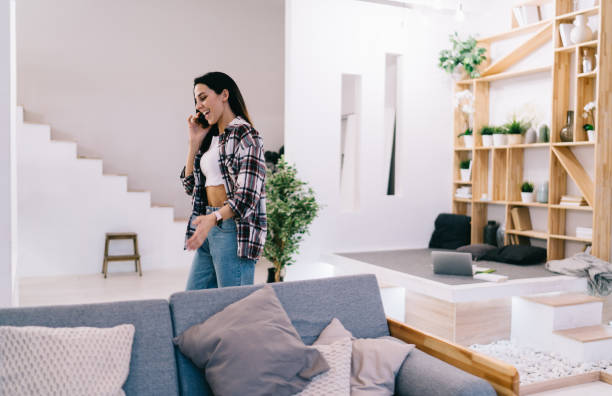 istock Laughing woman talking via phone and walking about room 1421978986