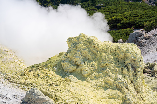 smoking solfatara among sulfur deposits on the slope of the volcano