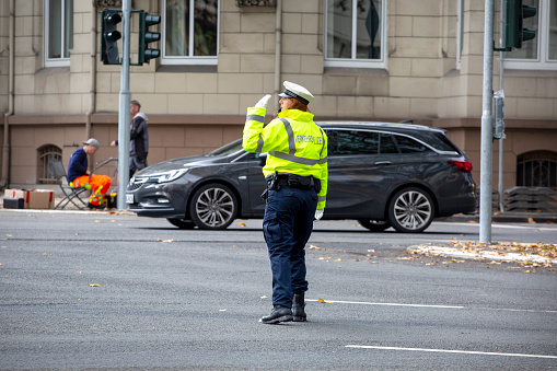 Wiesbaden, Germany - October 13, 2021: German traffic policewoman regulating the traffic during rush hour on a busy junction in the center of Wiesbaden, Germany