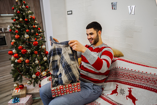 Man opening Christmas present while alone at home