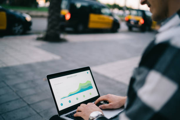 Cropped image of male digital nomad keyboarding and browsing web page with infographic working remotely on street, man millennial freelancer typing on laptop computer making research for project
