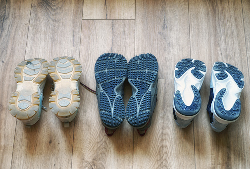 Young woman's legs in the warm, soft, comfortable slippers out of the bed on the wooden floor in the morning after waking up or in the evening before bedtime in the bedroom.