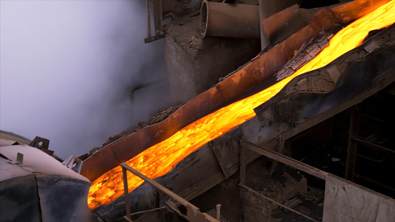 Liquid metal from flowing from blast furnace. Industrial background, melted metal or hot steel on the production line in the hot shop of the factory, professional equipment.