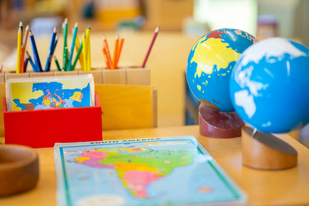 Montessori Classroom Set-Up A Montessori Geography classroom set-up complete with a world map, globes and pencil crayons all sitting out on a desk. montessori stock pictures, royalty-free photos & images
