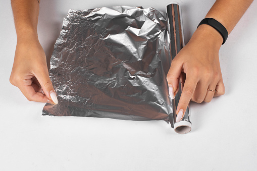 A woman tears off a piece of food foil for cooking.