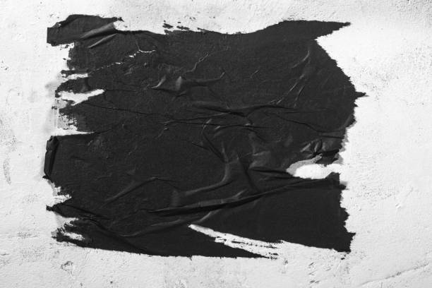 istock Scraps of black paper on a white wall. 1421993627