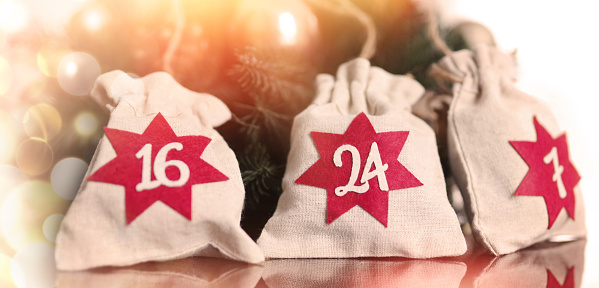 Advent calendar. Christmas bags with gifts on the background of a Christmas wreath and beautiful bokeh.