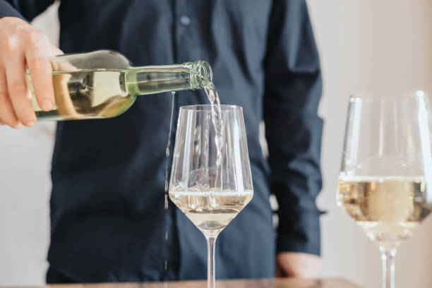 istock Sommelier pouring white wine from a bottle into a glass 1421995917