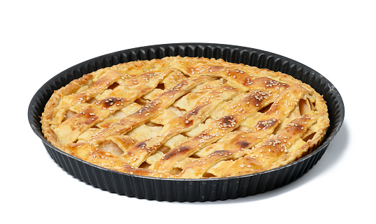 Round baked apple pie in a non-stick pan on a white isolated background