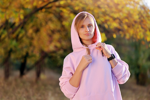 Pretty woman in a pink hoody in the autumn park