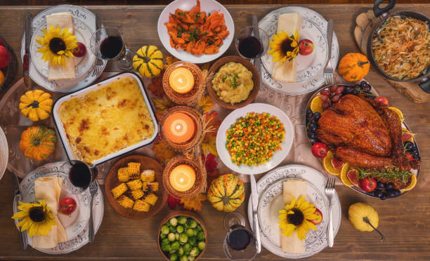 Table is set up for Thanksgiving celebration. On the table is a traditional stuffed roasted turkey with side dishes and pecan pie
