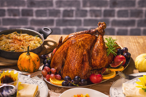 Roasted whole turkey on festive rustic table with autumn decoration for Thanksgiving Day