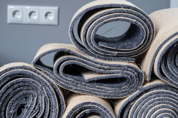 istock Stacked old carpet rolls in a grey room. 1421999778