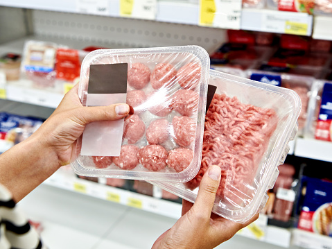 Buyer woman chooses chopped meat in a shop