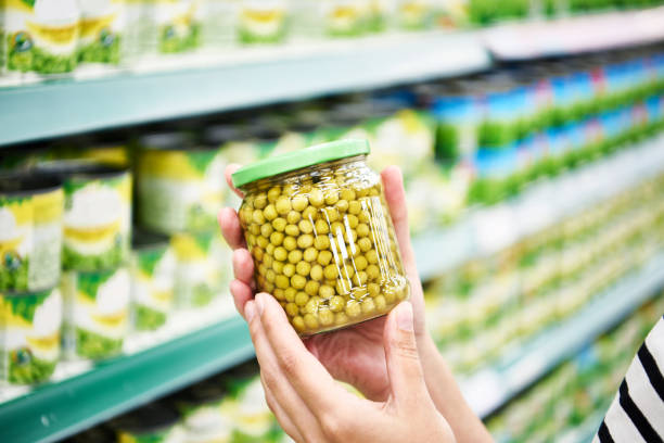 istock Green peas in glass jar in hands at store 1422001006