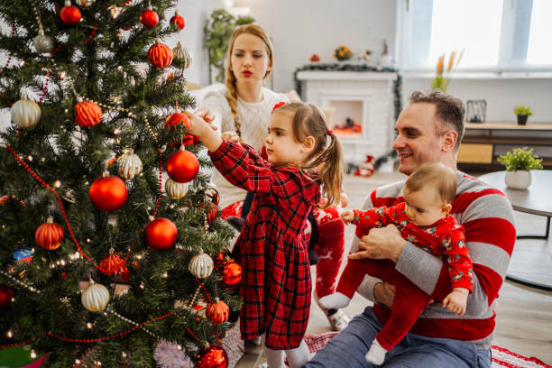 istock Young family with three children decorating a Christmas tree 1422001998