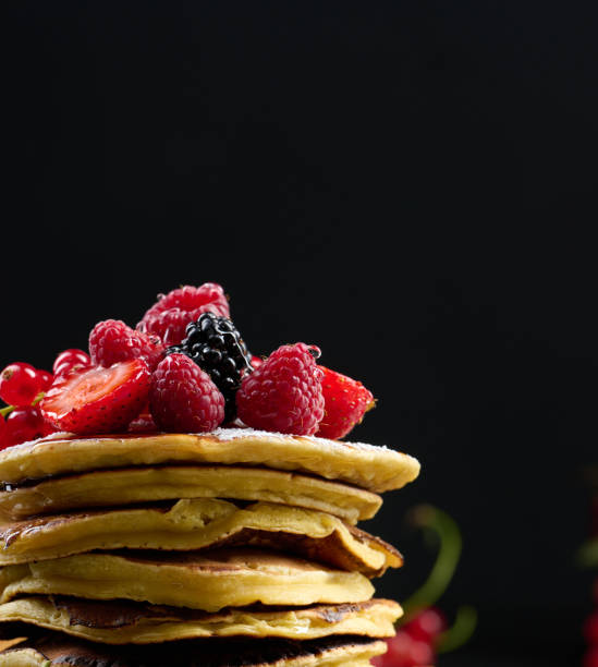 istock A stack of pancakes with fresh fruits poured with syrup on a black background 1422005620