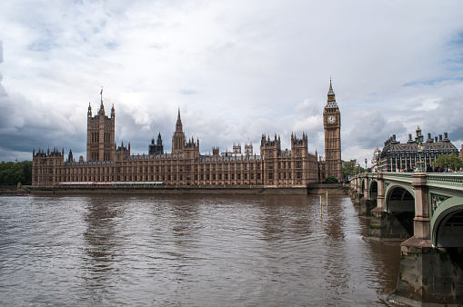 The Houses of Parliament in London with the Big Ben tower and bell in the Westminster Borough. Bridge over the River Thames with embankment.