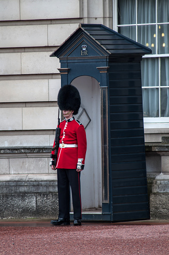 London, United Kingdom - 10 July 2012: A royal soldier in a red uniform with a large cap stands on the ramparts of Buckingham Palace in London.