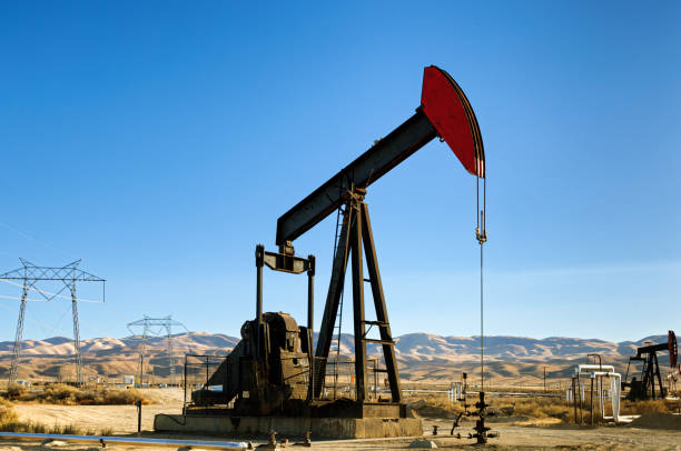 Lost Hills Oil Field pumpjack, with power pylons\n in background.\n\nTaken in the Lost Hills Oil Field in Kern County, California, USA.