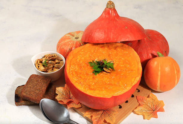 Pumpkin and zucchini cream soup with roasted seeds and toast in hollowed out pumpkin,traditional autumn vegan food,baked in the oven,healthy natural breakfast,