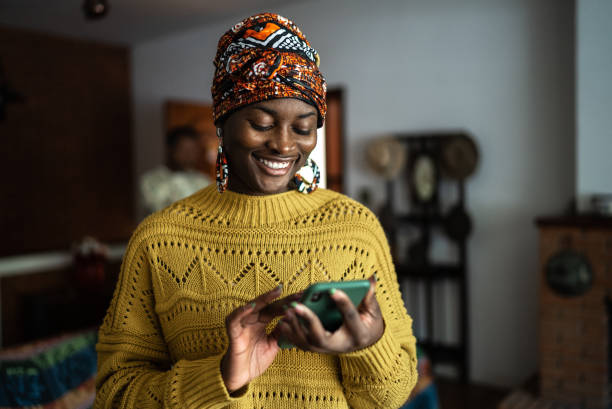 自宅で携帯電話を使う若い女性 - technology mobile phone clothing smiling ストックフォトと画像