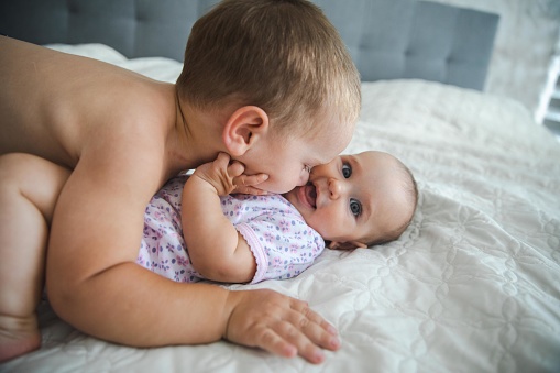 Cute older brother hugging his six months old daughter