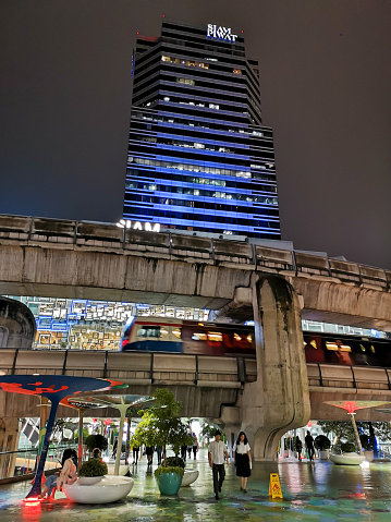 Bangkok, Thailand - September 10, 2019:  Bangkok cityscape showing high-rises and running BTS skytrains with cloudy blue sky at night with Siam Piwat Tower, a 30-storey exclusive office building in the center