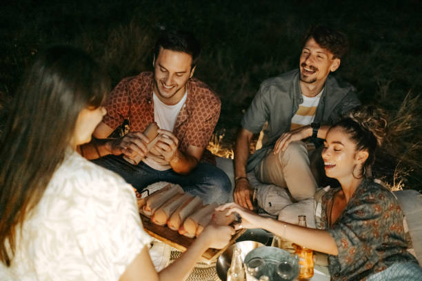 Friends enjoying hot dogs while camping outdoors stock photo