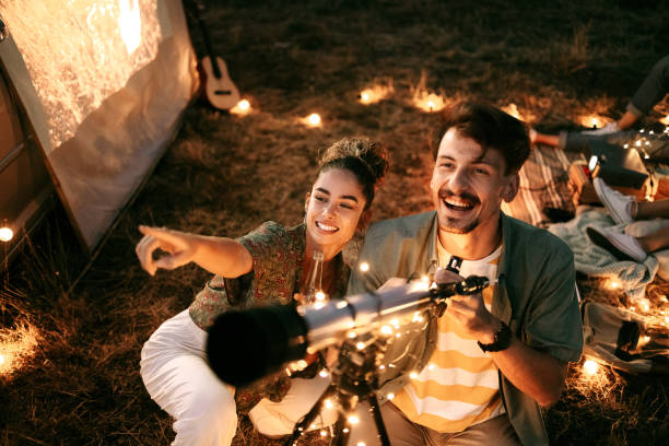 Couple stargazing together with a astronomical telescope