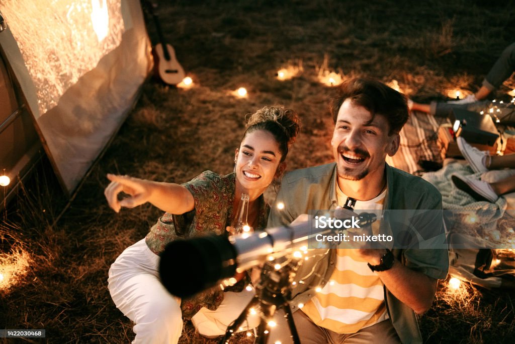 Couple stargazing together with a astronomical telescope Couple stargazing together with a astronomical telescope while being on a romantic date Astronomy Stock Photo