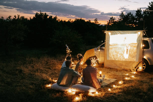自然の中で屋外で映画の夜を楽しんでいる友人のグループ - プロジェクター ストックフォトと画像