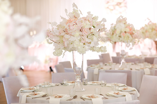 festive wedding decoration. Beautiful fresh white and pink flowers in glass vase on dining table on wedding day. High quality photo.