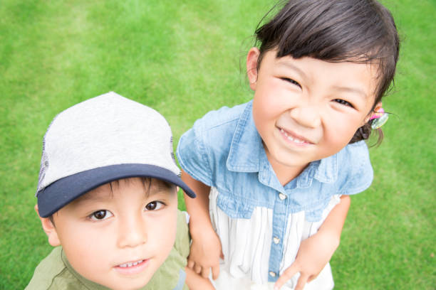 Siblings smiling in a park with lots of greenery
