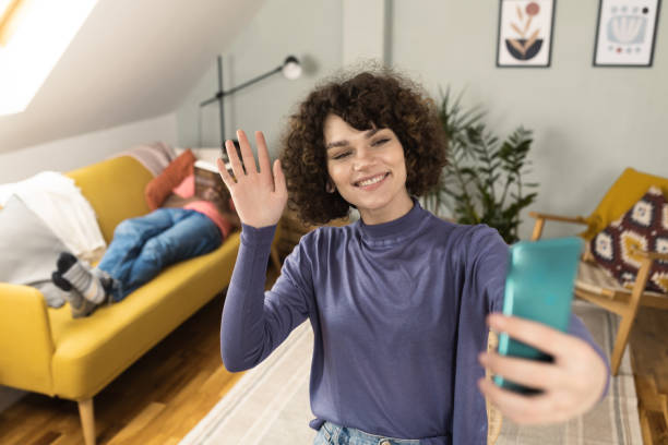 istock Beautiful girl taking a selfie while her boyfriend reading on the sofa 1422055116