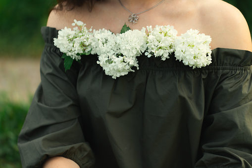 Portrait of an attractive woman with a Viburnum flower in her lips. Front view.