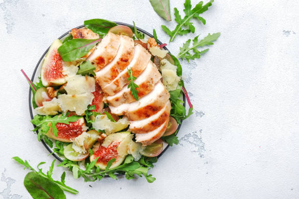 istock Grilled chicken fillet with fig, grape, arugula and chard salad. White kitchen table background, top view 1422063204